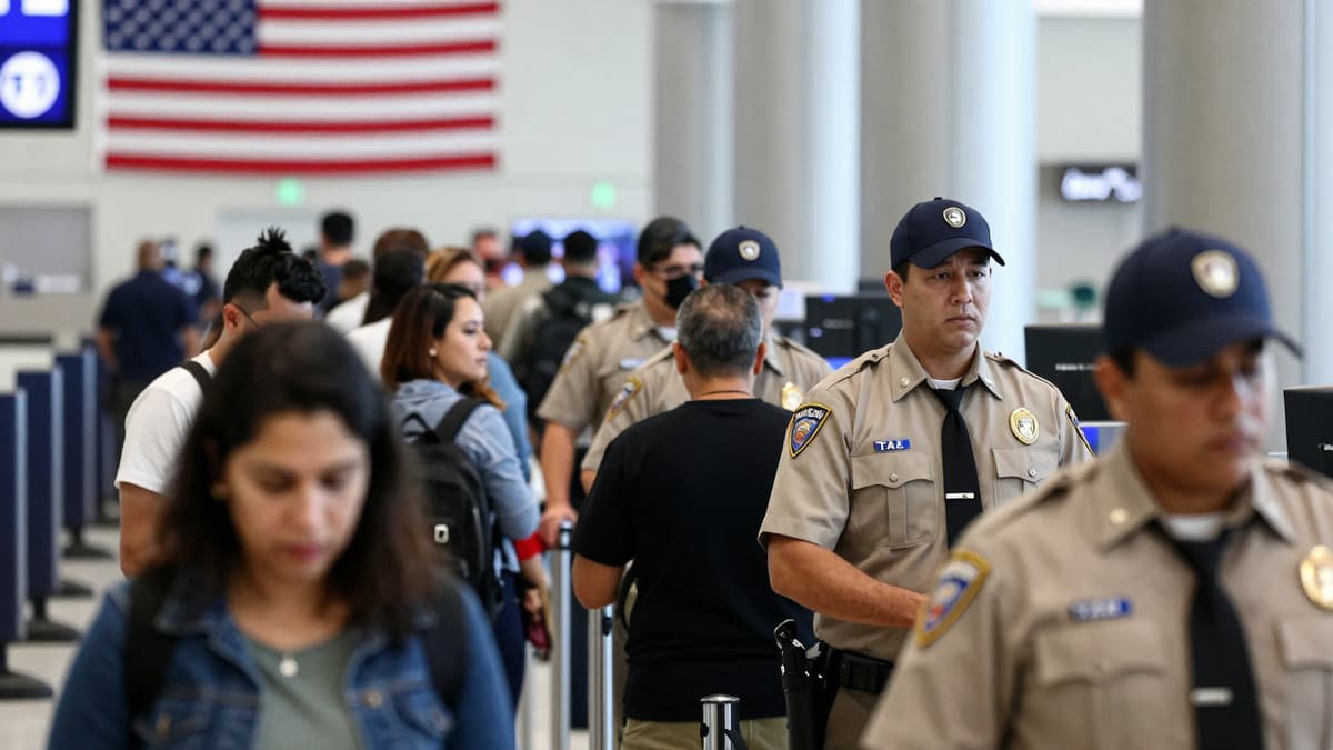 Crowded airport security line with travelers and agents highlighting delays during a funding dispute.
