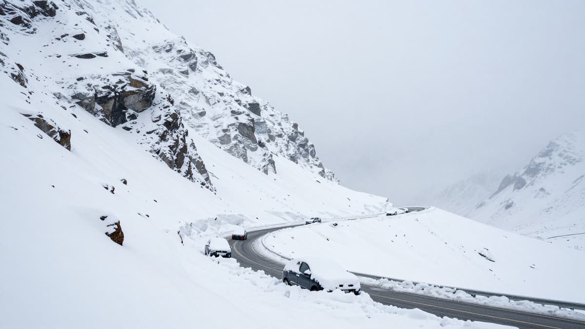 Snow-covered mountain pass with buried vehicles after a massive avalanche on a high-altitude road.