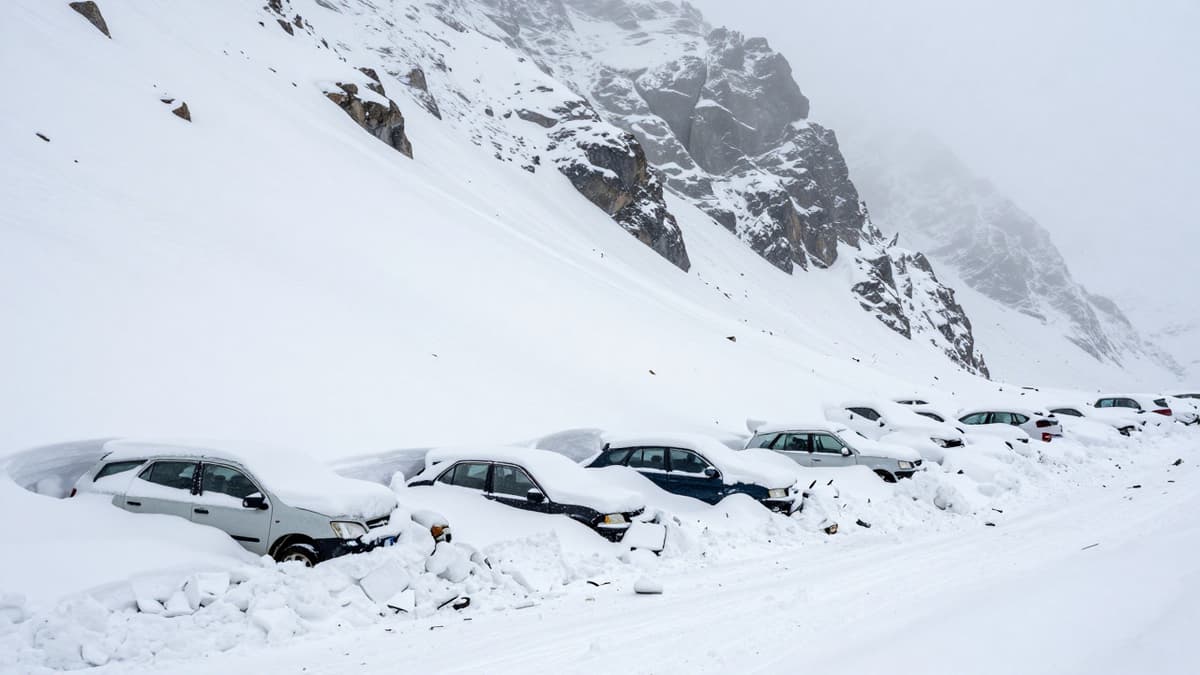 Snow-covered vehicles buried under a massive avalanche at a high mountain pass