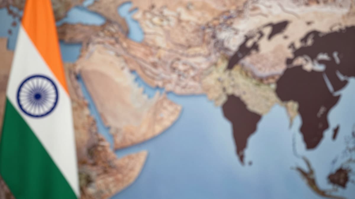 Blurred map of India and Middle East with Indian flag at a press conference setting.