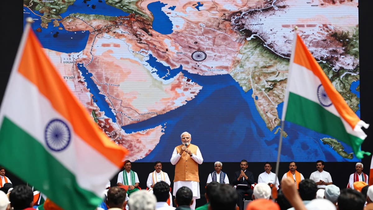 Prime Minister addressing a rally with a backdrop showing the Middle East conflict map and flags.