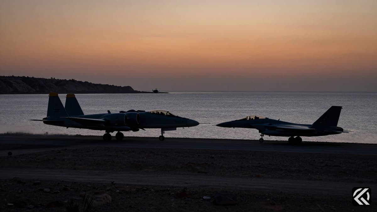 Military aircraft silhouettes flying over the Strait of Hormuz at dusk, depicting a tense aerial conflict scene.