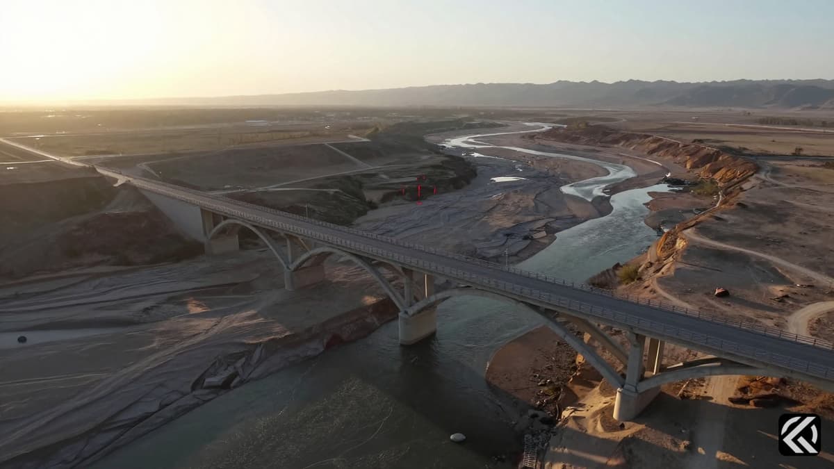 Aerial view of a concrete arch bridge in an arid landscape with a digital target symbol on the structure.