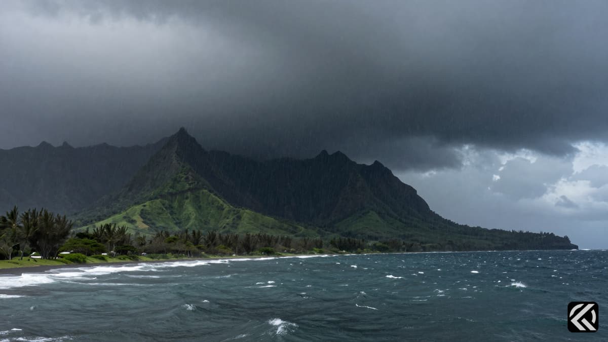 Dark storm clouds and heavy rain over lush Hawaiian volcanic terrain during a severe weather event.