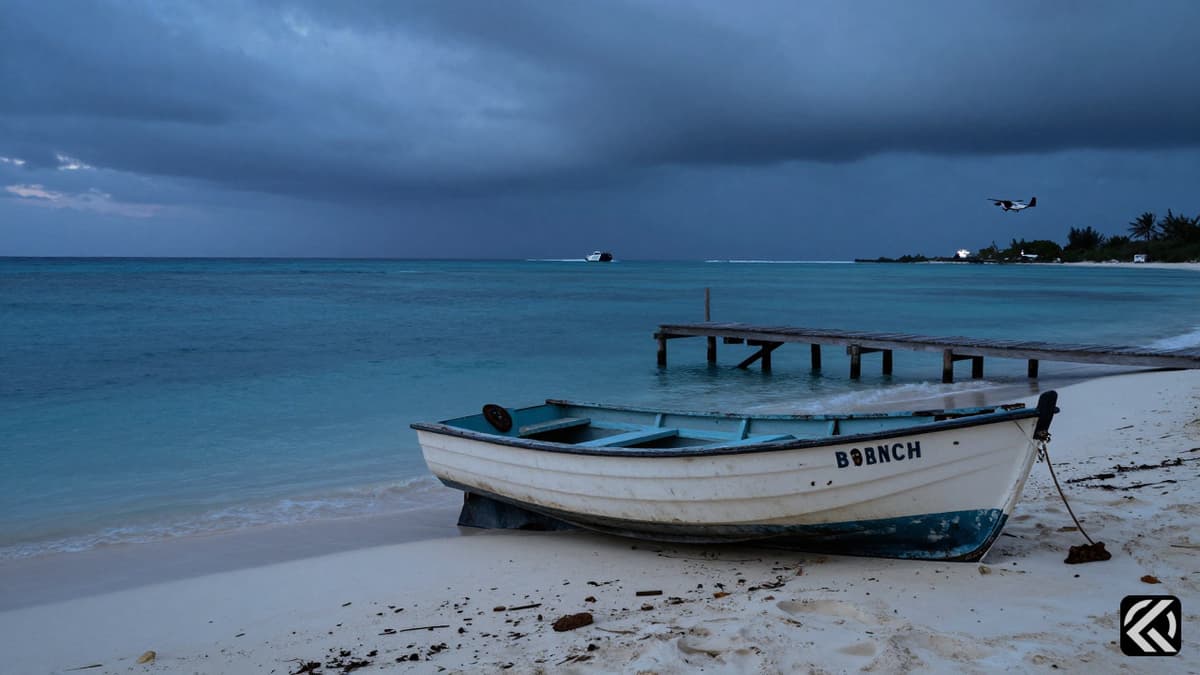 A beached dinghy and police presence at a Bahamian boatyard under a cloudy sky.