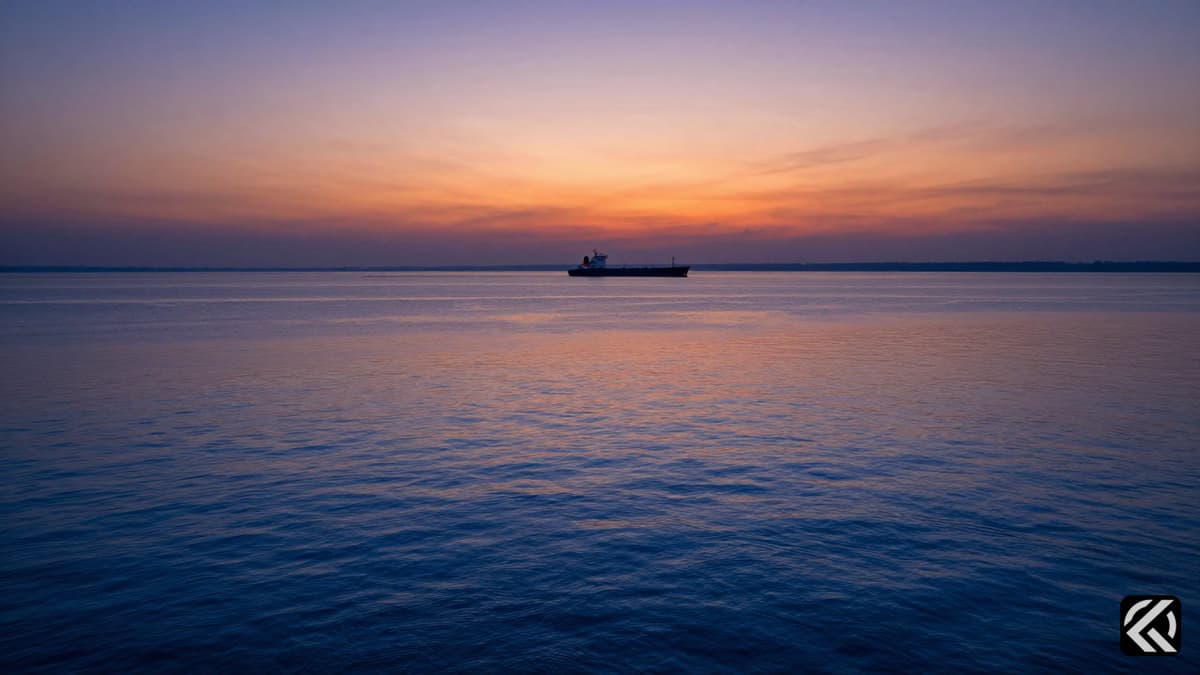 Calm waters of the Strait of Hormuz at sunset with a distant ship silhouette